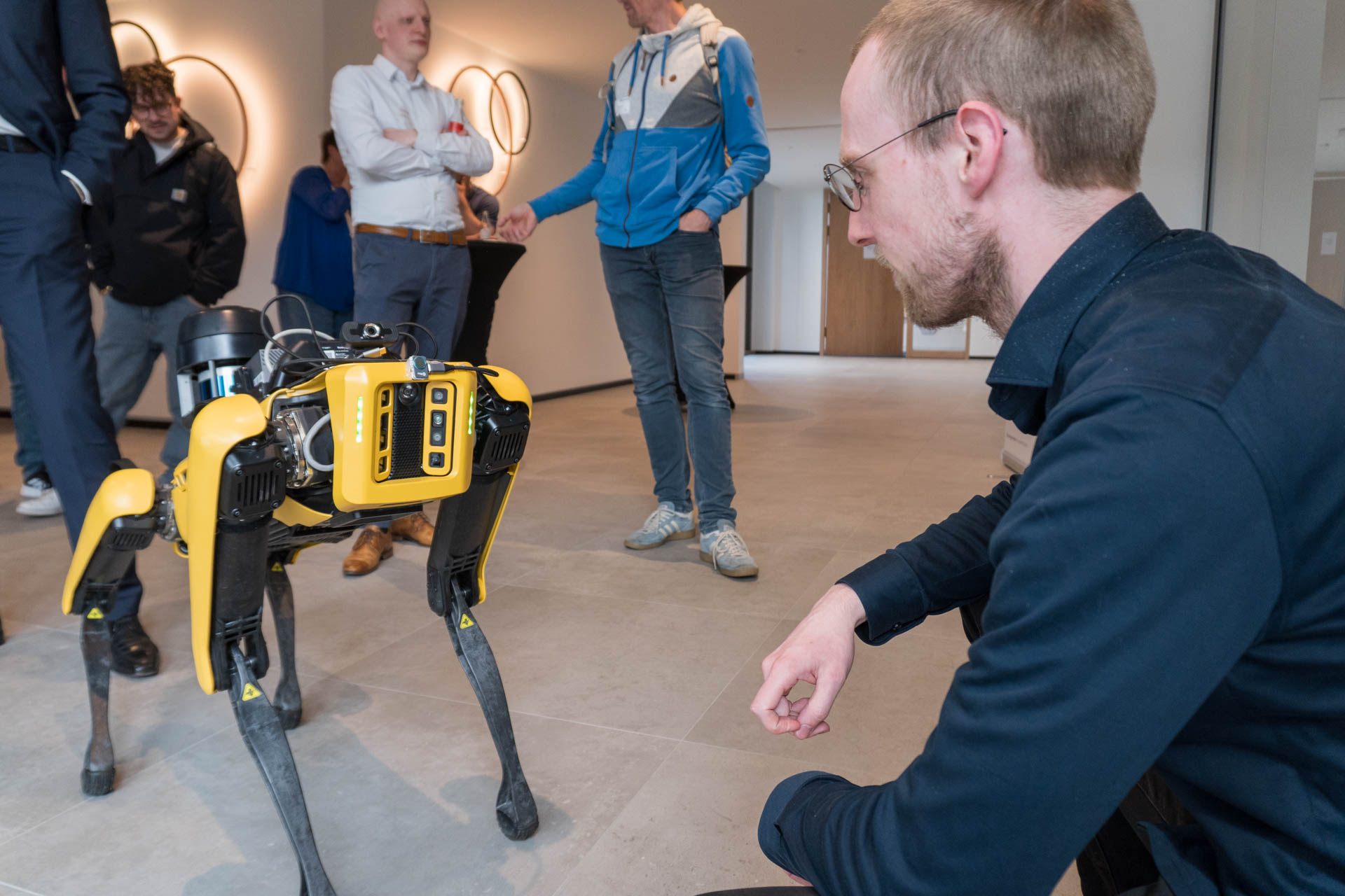 Ein Mann und ein Roboterhund hocken sich gegenüber